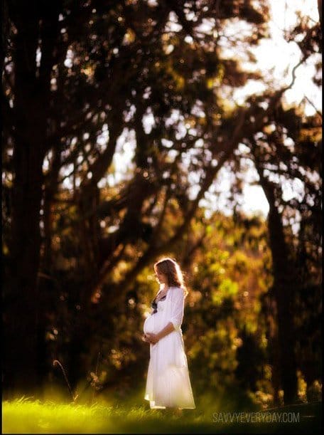 maternity photo of mom at the park in a white gown