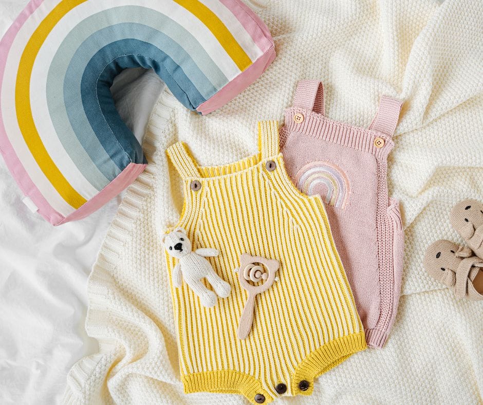 flatlay of baby girl clothes and rainbow