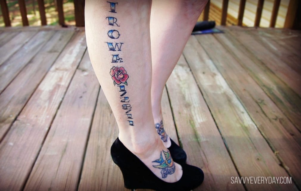 Close up of the side of woman;s leg with a tatoo that says "Trowa" then has a red rose and the date 1/28/11.