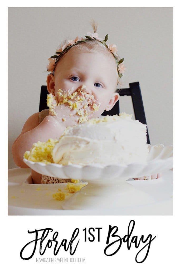baby eating birthday cake in white highchair