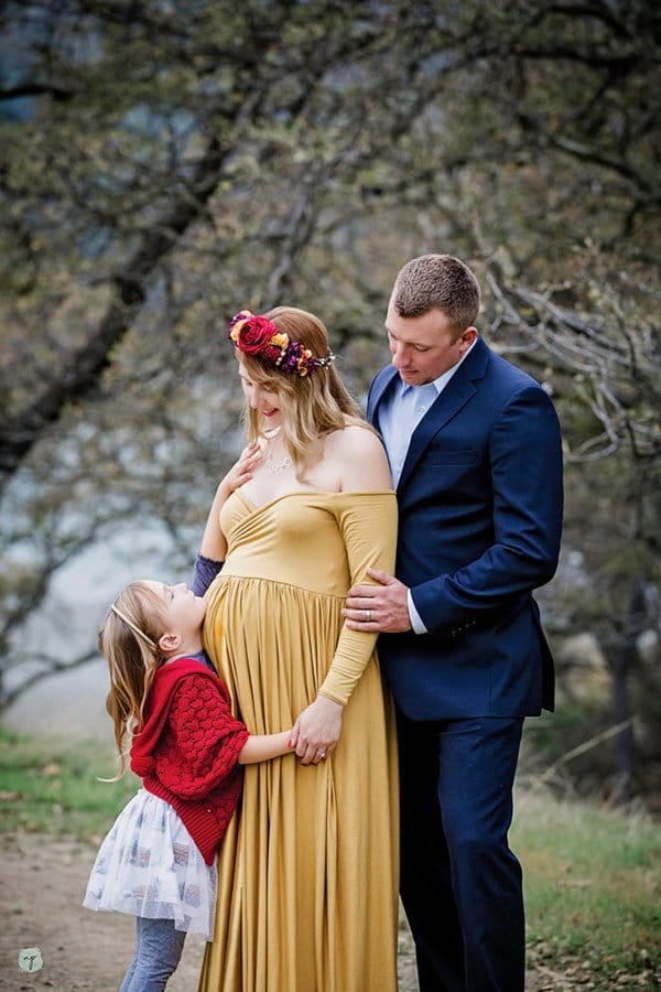 family maternity photo- girl reaching for mom with dad behind mom