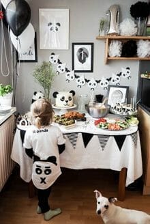 boy wearing panda t-shirt staring at panda-themed birthday treat table with a panda cake