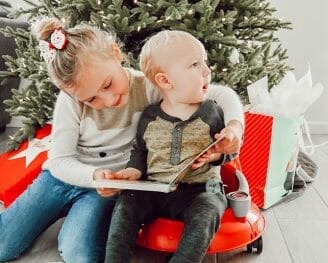 River and S reading a book by the Christmas tree