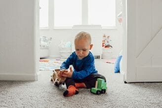 Boy playing with truck set between the shared kids room spaces
