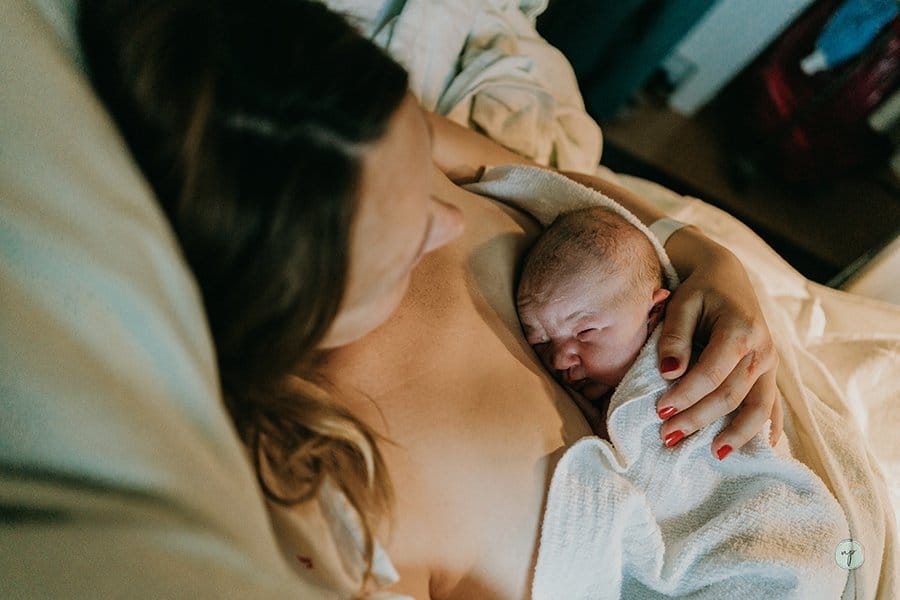 baby laying on mother's chest during golden hour