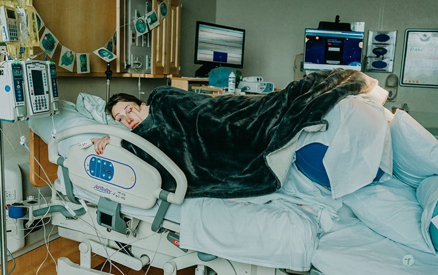 birthing mom in hospital bed under blanket
