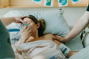 birthing mom holds nitris oxide mask over face | How Parenthood Transforms Us