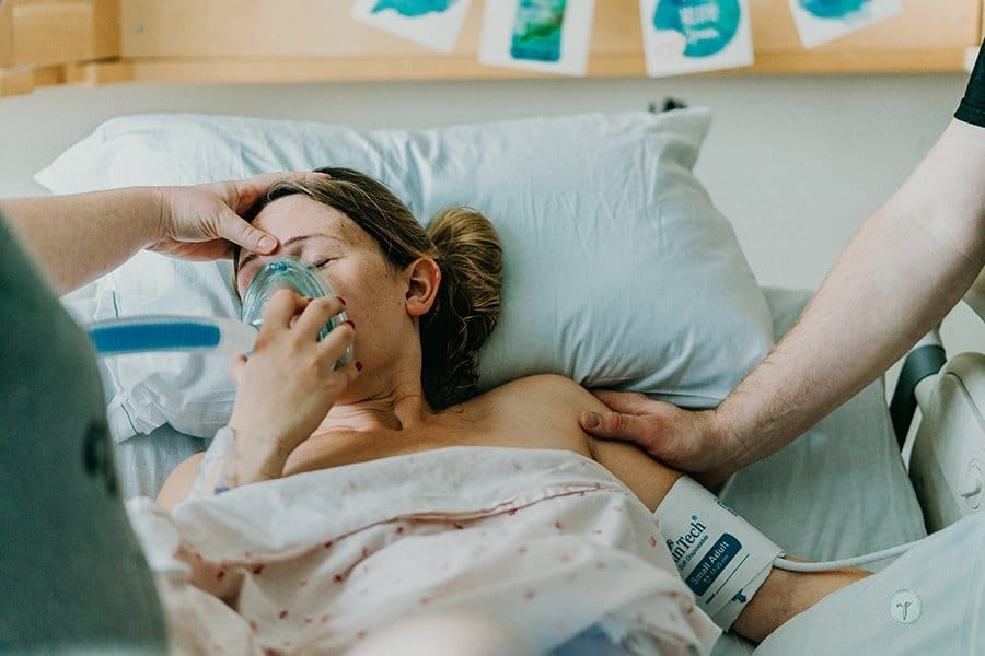 birthing mom holds nitris oxide mask over face