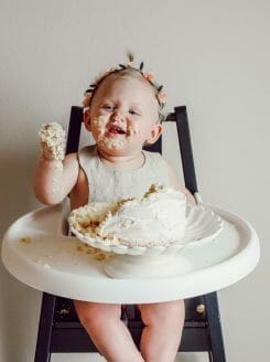 happy baby in highchair eating birthday cake