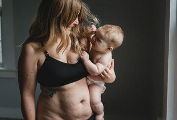 postpartum mom in black bra with baby on her hip