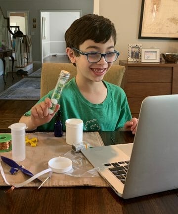 boy smiling at laptop while holding gem project