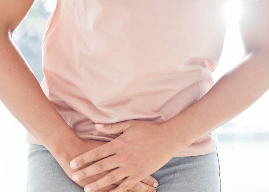 woman holds her thigh for pelvic pain