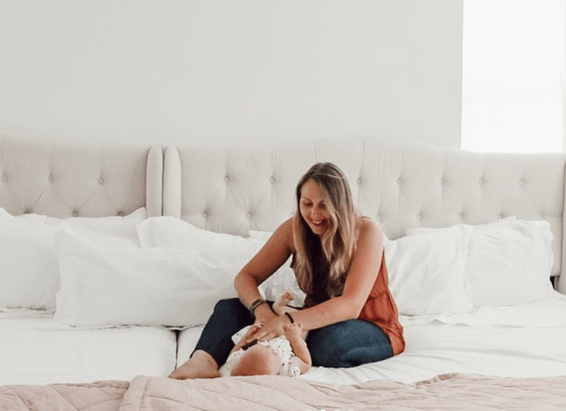 mom on bedsharing bed with baby + pros and cons of bed sharing