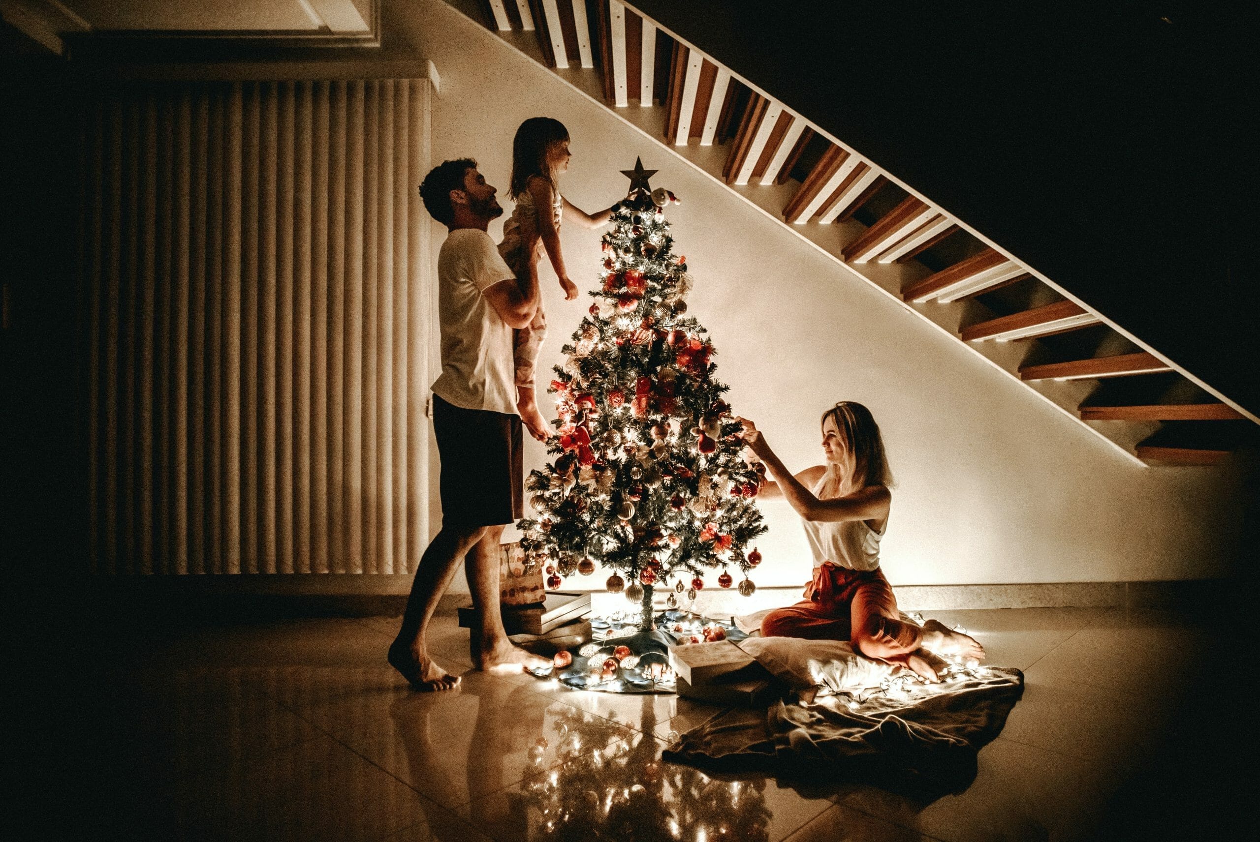 family by Christmas tree at night