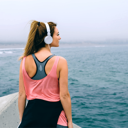 woman in workout clothes looks out at ocean