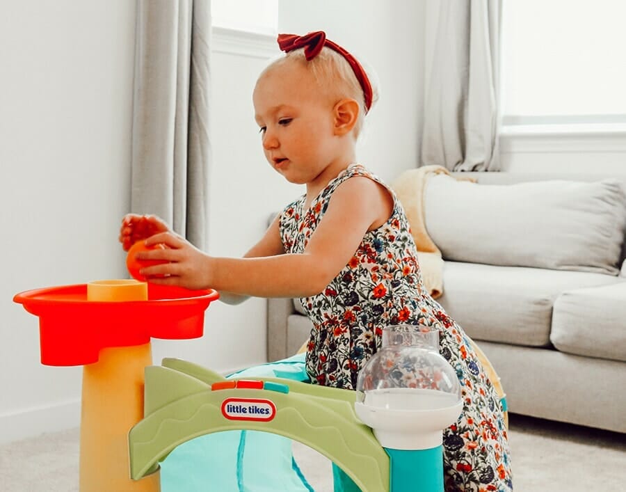 toddler drops ball in activity tunnel