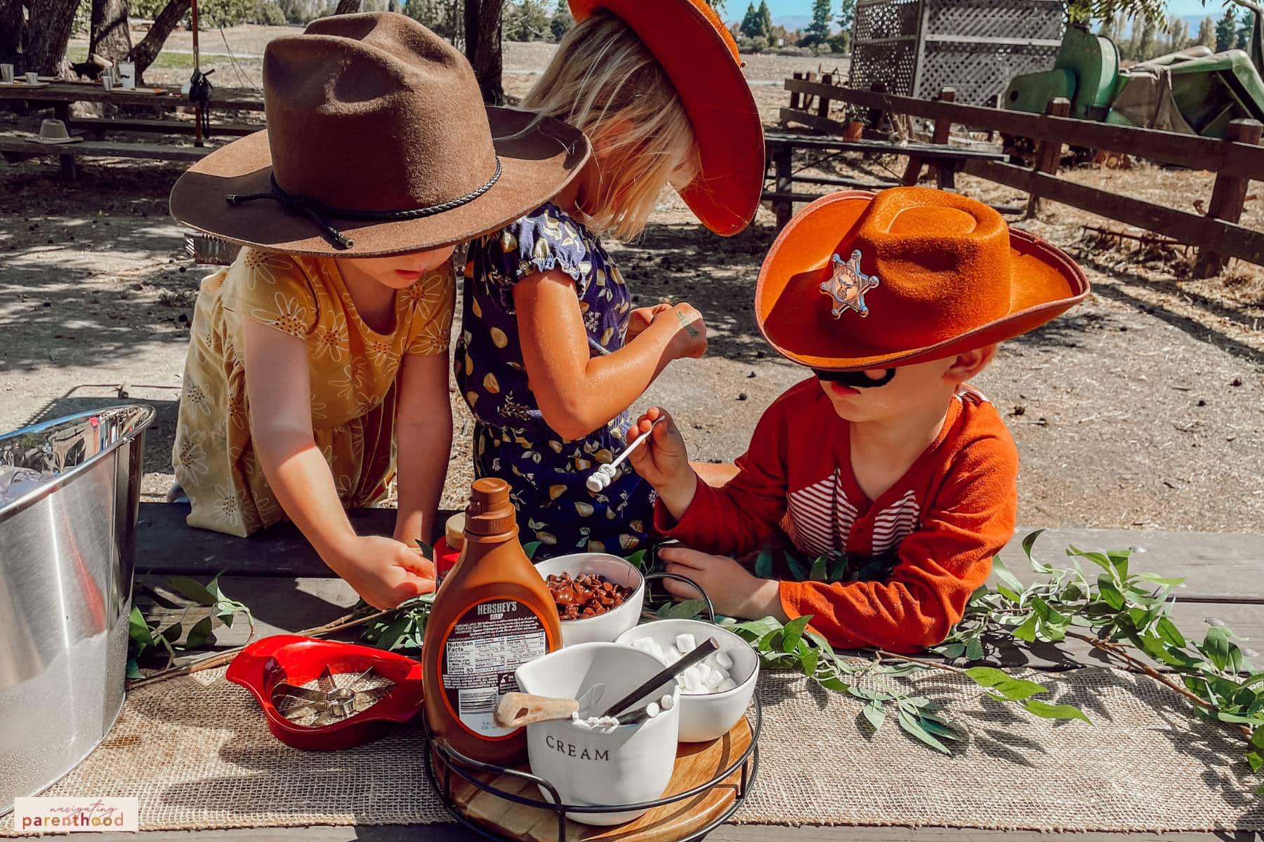 three kids decorating apples at the Wild West birthday apple picking activity