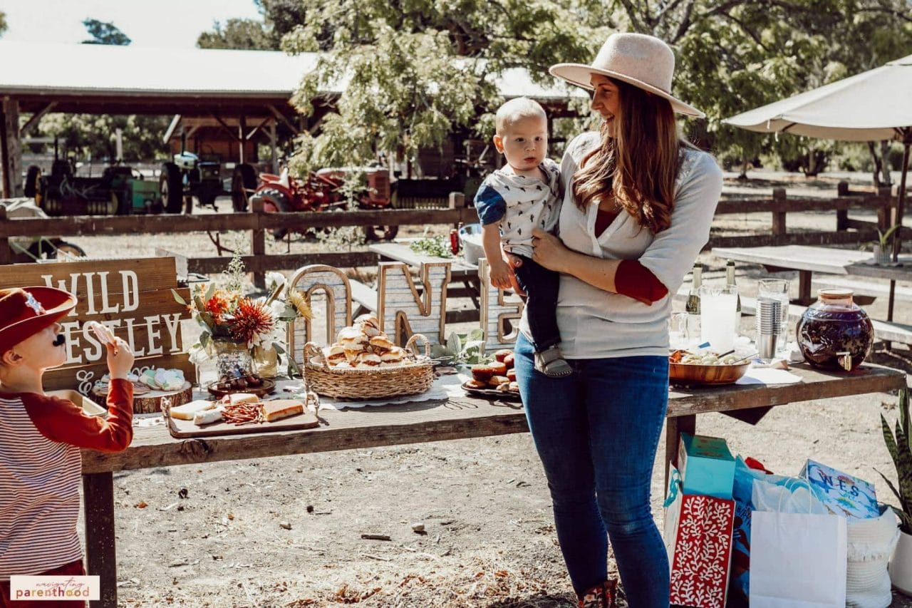 Shari holds Wes at Wild West first birthday party food table