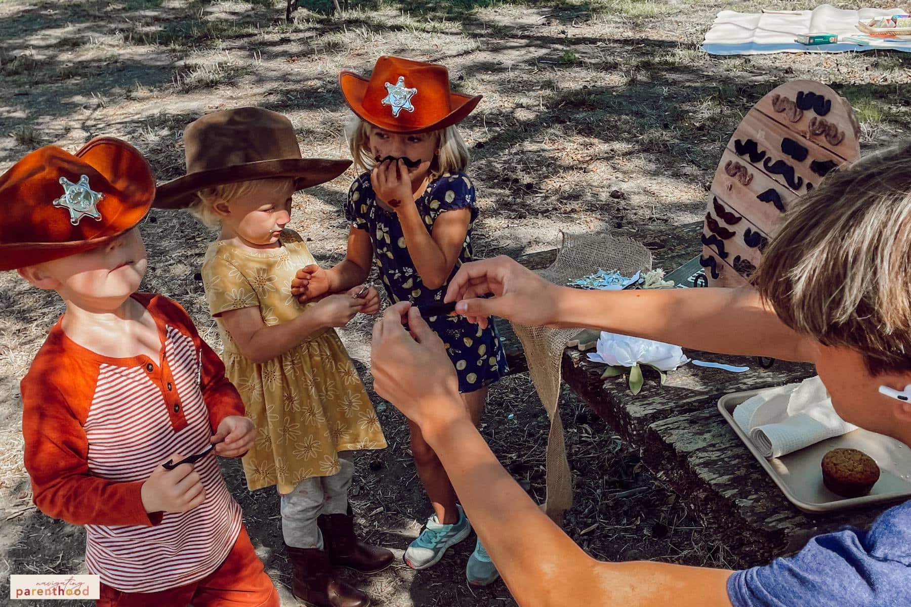 kids getting mustaches at wild west birthday