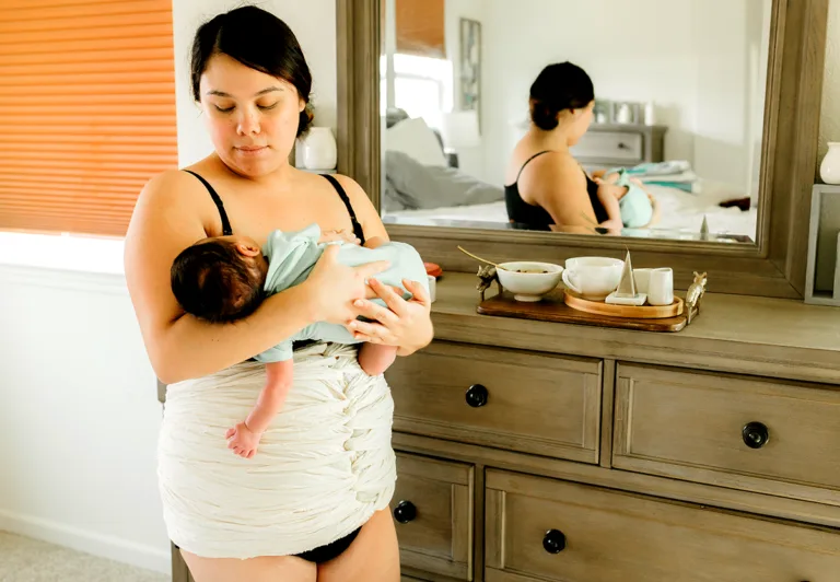 newborn mother wearing belly bind holds her baby